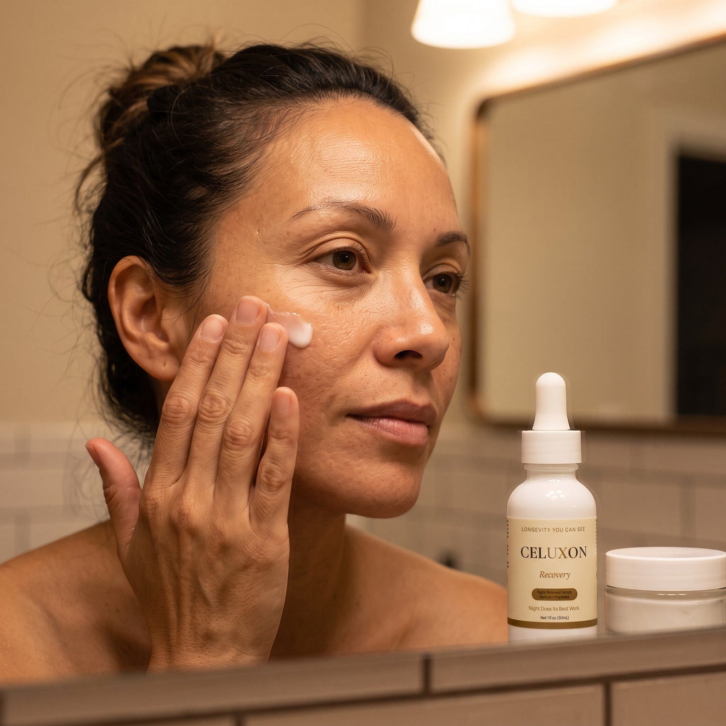 A woman applies cream to her cheek in a bathroom setting, with a bottle labeled CELUXON Recovery and a small jar on the counter in the foreground.